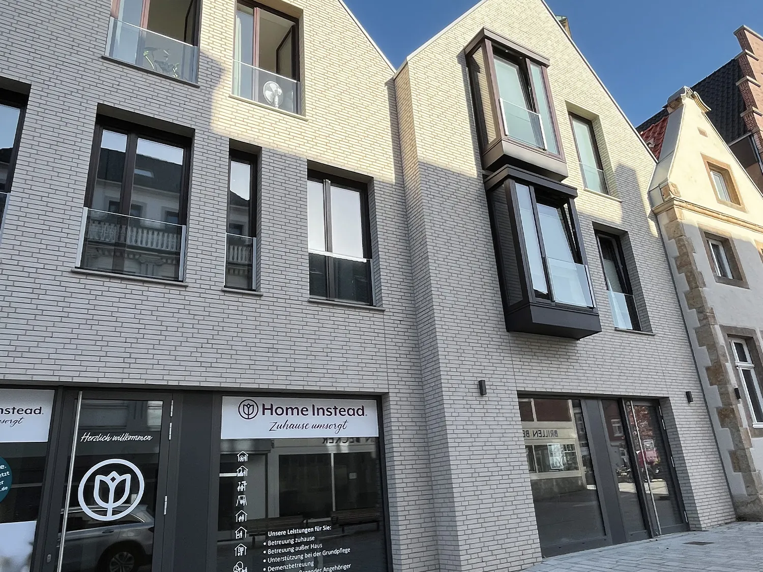 Modernes Wohn- und Geschäftshaus mit heller Fassade mit vielen, großen Fenstern