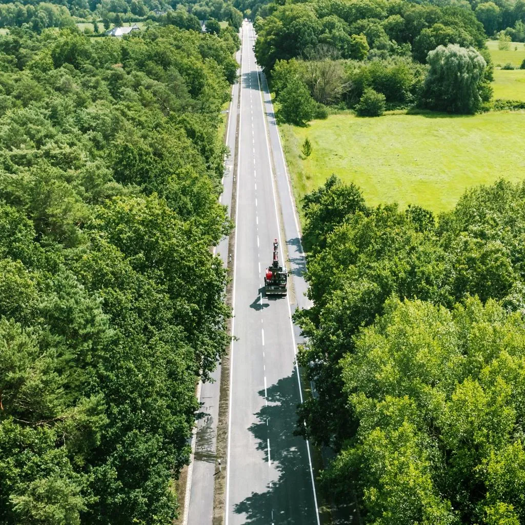 Straße zwischen Bäumen und Feldern