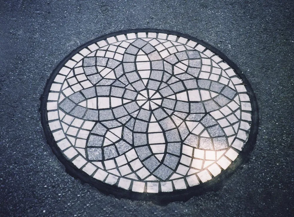 Runder Mosaik in Naturstein-Look in einer Asphaltfläche