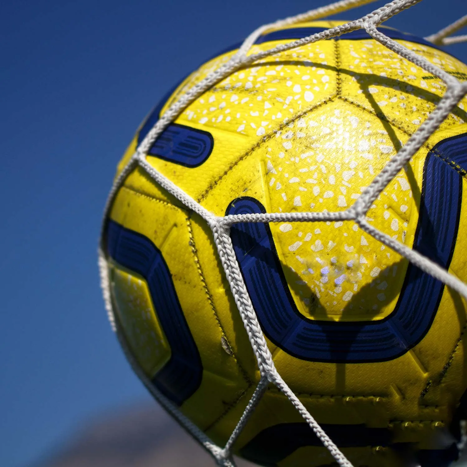 Fußball im Tornetz vor blauem Himmel
