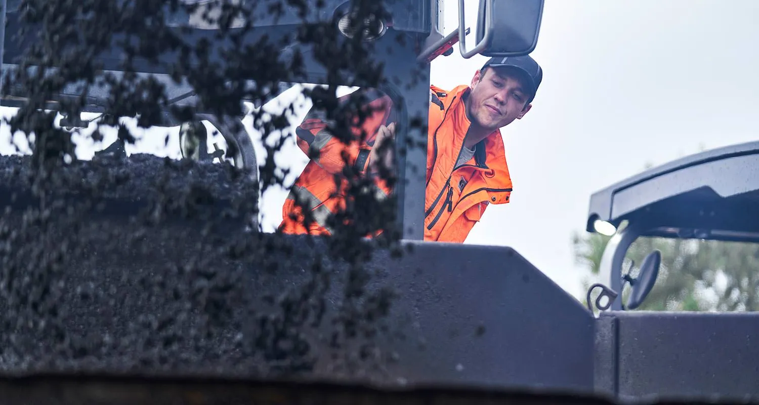 Mitarbeiter auf einer Asphaltbaumaschine bei der Arbeit