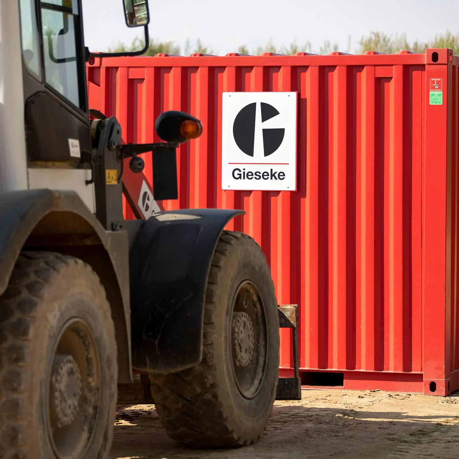 Radlader vor rotem Container mit Gieseke-Logo