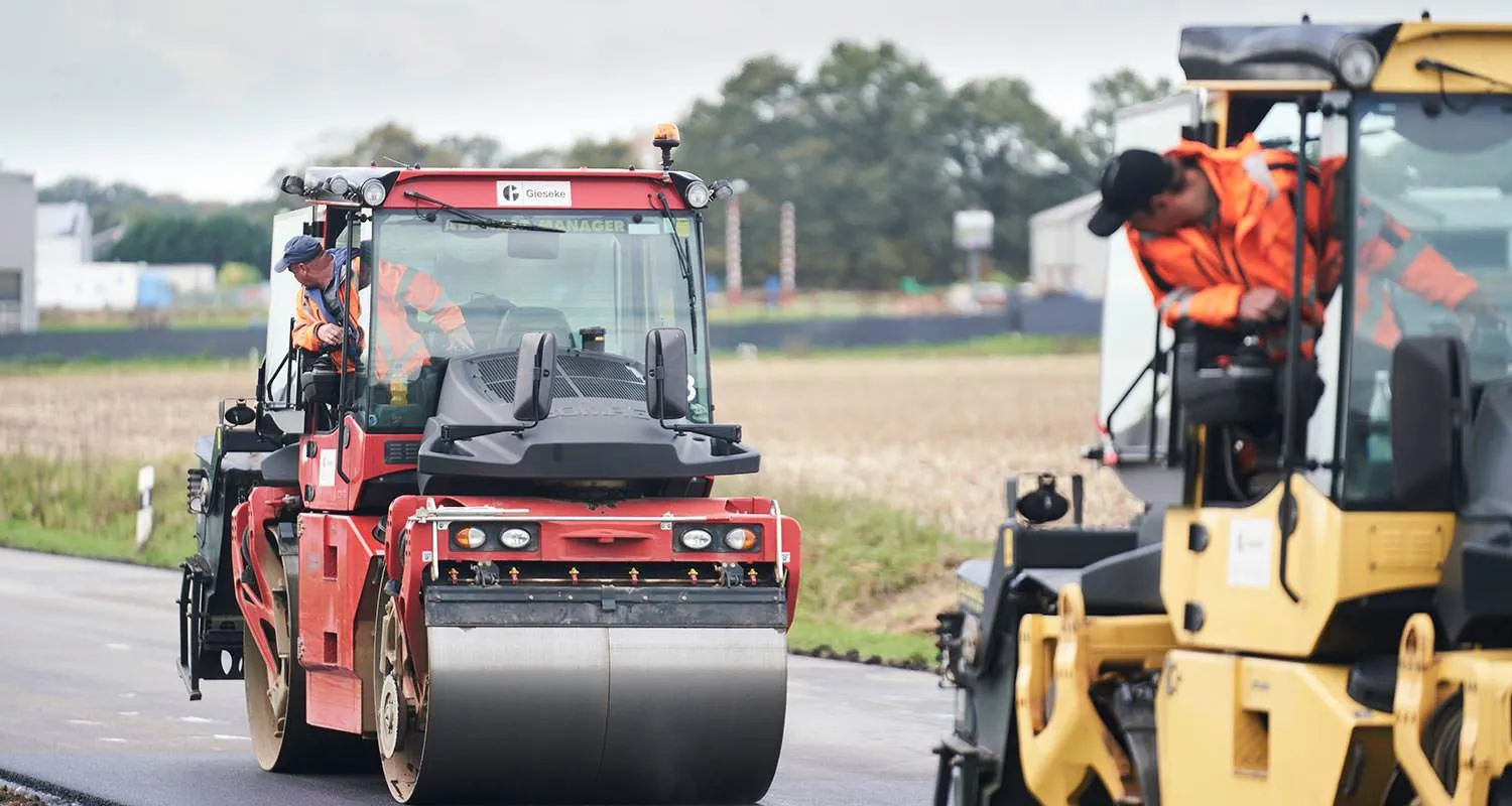 Straßenwalze und Asphaltfertiger im Einsatz auf einer Landstraße