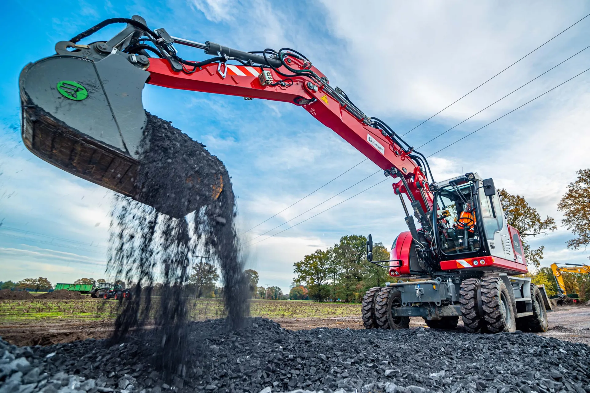 Bagger beim Verladen von Asphaltfräsgut auf einer Baustelle