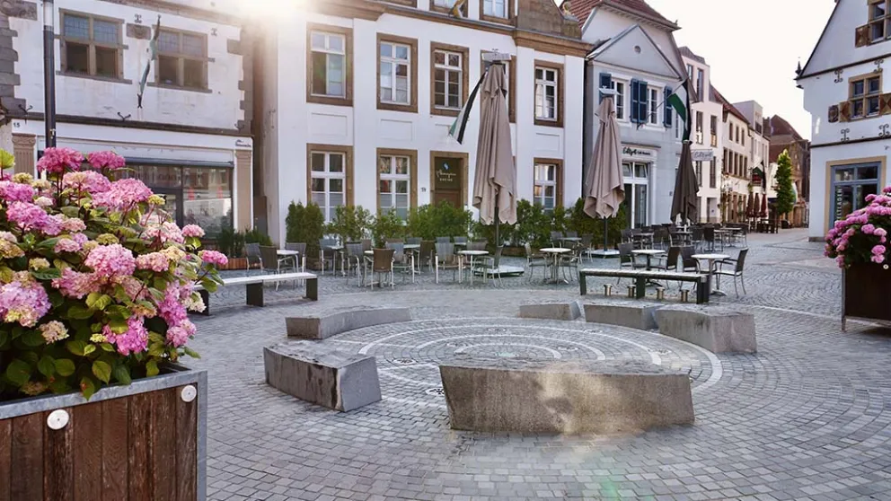 Neu gestalteter Stadtplatz mit Pflanzkübeln, Sitzgelegenheiten und Pflasterfläche