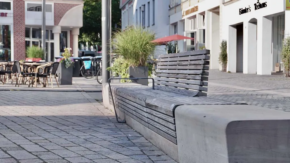 Sitzbank auf gepflastertem Stadtplatz vor Geschäften
